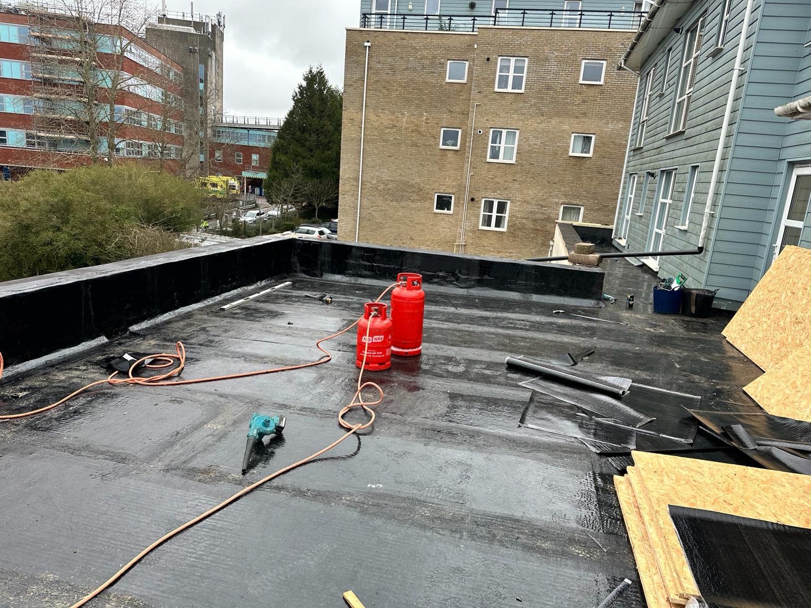 EPDM rubber flat roof installation in progress on a Portsmouth commercial building with gas torch and rolled membrane