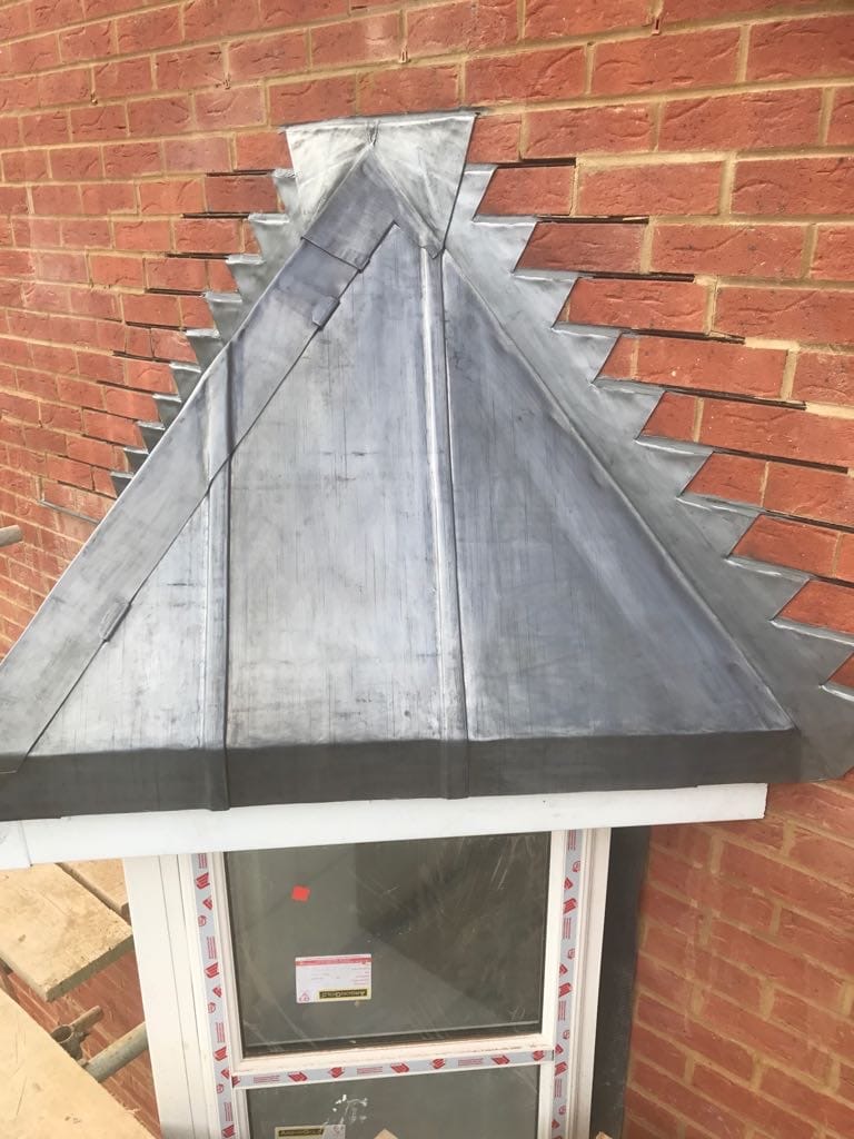 Hand-formed code 5 lead pyramid bay window roof with stepped flashing into brickwork on a Hampshire property